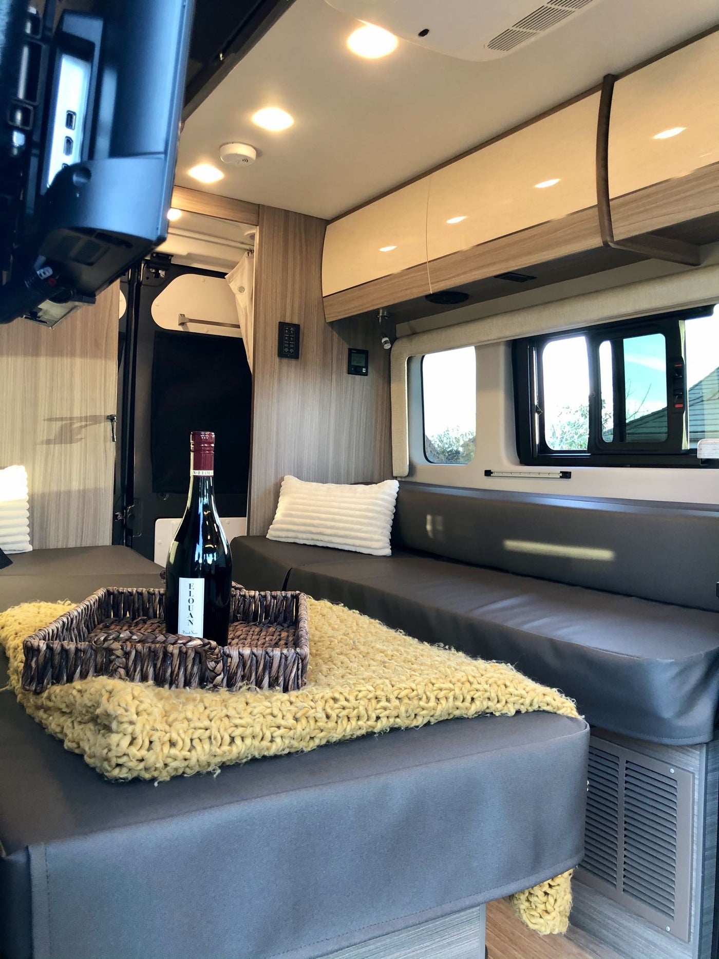 Cozy RV rental interior featuring a bottle of wine, comfy seating, warm lighting, and a view, ideal for your next road trip. — photo 5