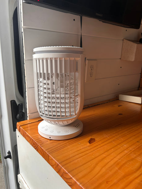 Portable fan/cooler on a wooden counter inside an RV rental. Provides comfort within the campervan's interior.