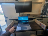 Cozy RV rental interior transformed into a compact mobile office and kitchen, featuring a laptop and monitor setup.