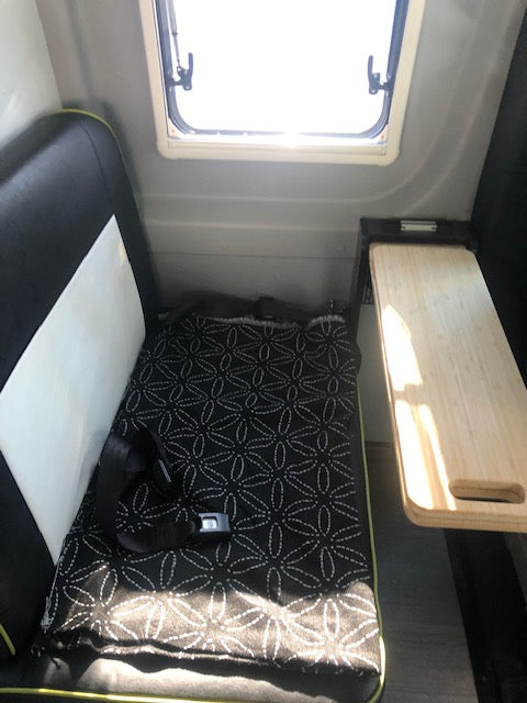 RV rental interior: A window, pull-out table, and patterned seat with seatbelt offer compact comfort.