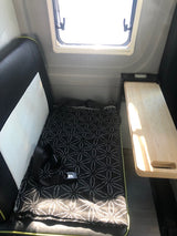RV rental interior: A window, pull-out table, and patterned seat with seatbelt offer compact comfort.