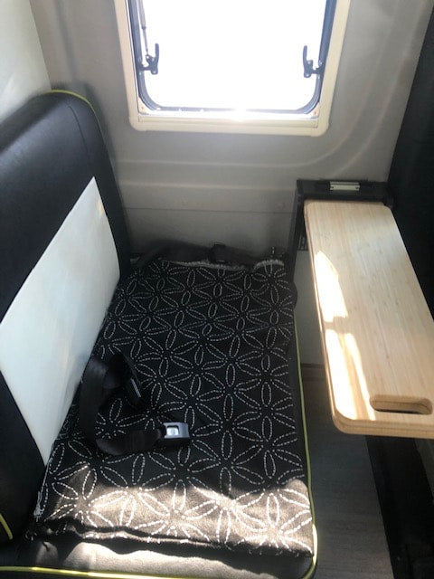  plus convenient paper towel holder.|Inside a comfortable RV rental: a bed with a 'SKI LODGE' pillow and views of nature outside the camper windows.|RV rental interior: A window — photo 8