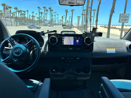 Inside a Mercedes-Benz RV rental, navigating a sunny coastal road with palm trees and the beach in view. Ready for adventure!