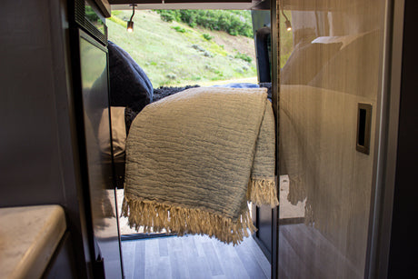 Experience comfort in this RV rental: a cozy bed inside with a stunning mountain landscape view from the rear.