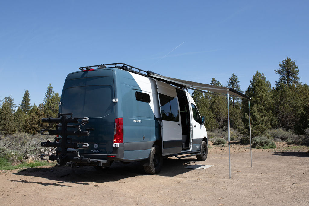 Custom two-tone rv rental camper van with extended awning & bike rack, ready for outdoor adventure.