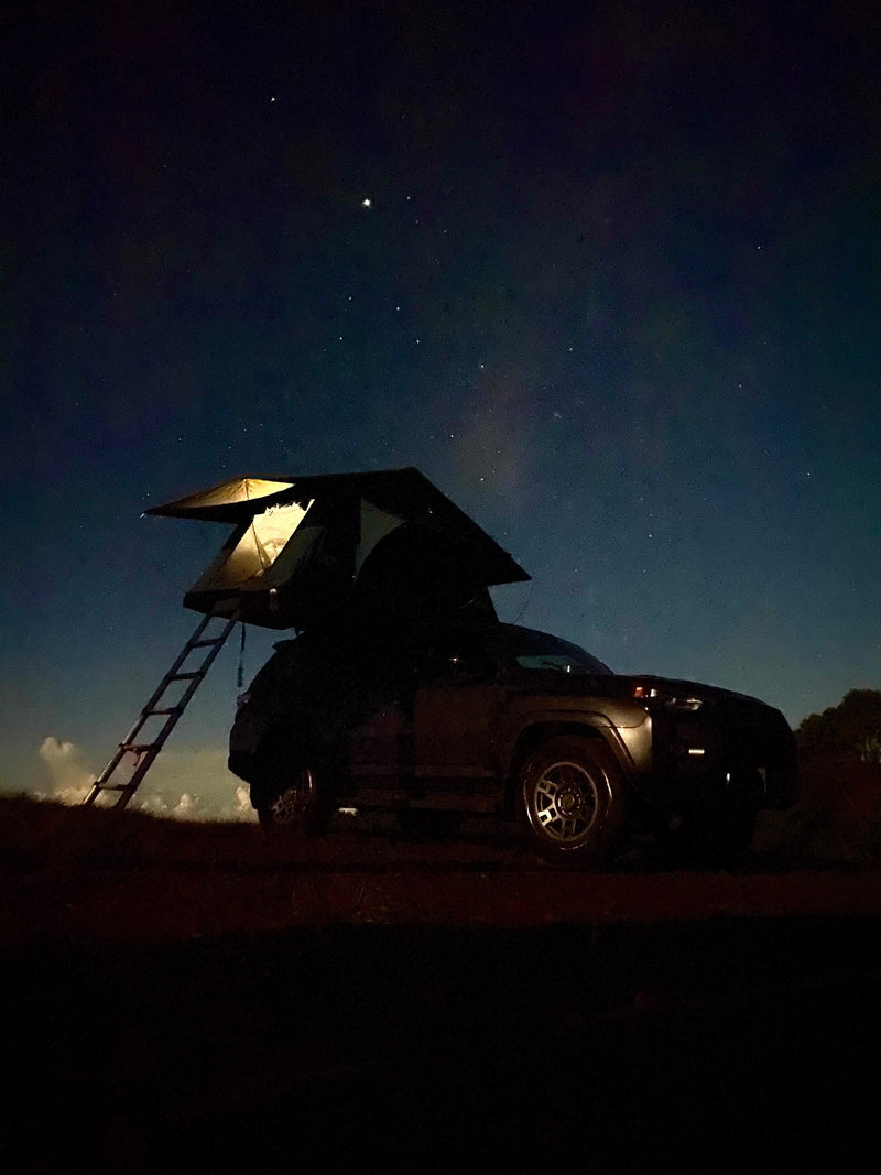 A car with an illuminated rooftop tent under a starry night sky, offering a unique RV rental camping experience. — photo 16