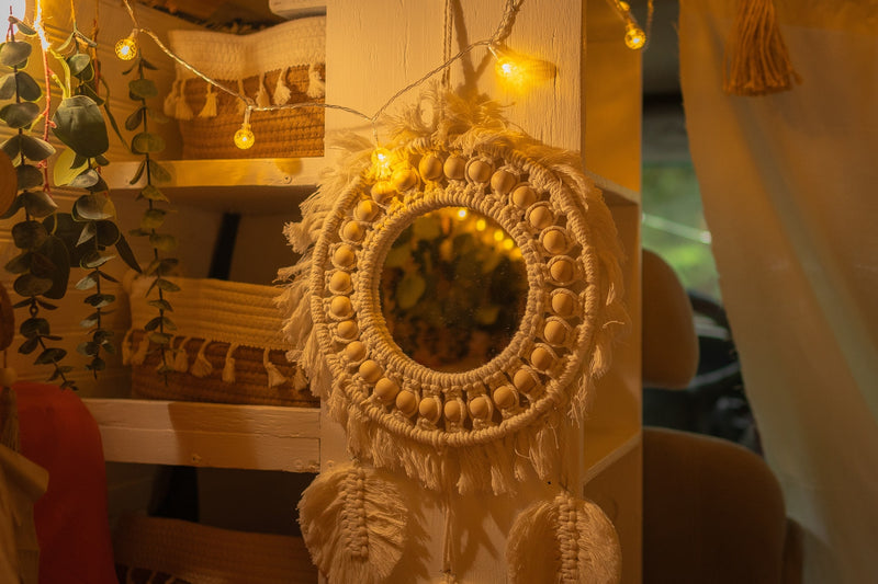 Warm RV rental interior: macrame mirror with beads, string lights, and shelves with woven baskets and plants. — photo 11