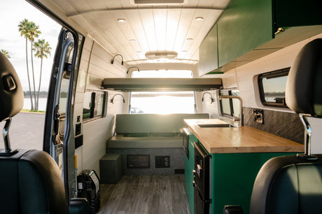 Step inside this rv rental van: a cozy mobile home with a kitchen, sleeping area, and water view.