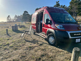 Enjoying a sunny day with an RV rental camper van parked in a scenic natural park. Chair set up outside.
