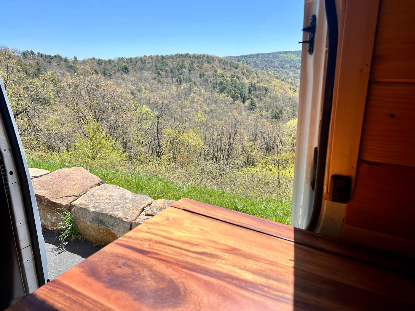 An RV rental provides this stunning spring mountain view. Light green trees fill the valley, framed by a cozy wooden interior. — photo 8