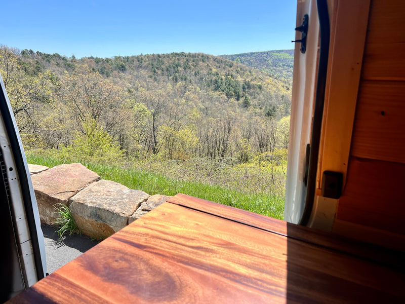 An RV rental provides this stunning spring mountain view. Light green trees fill the valley, framed by a cozy wooden interior. — photo 8