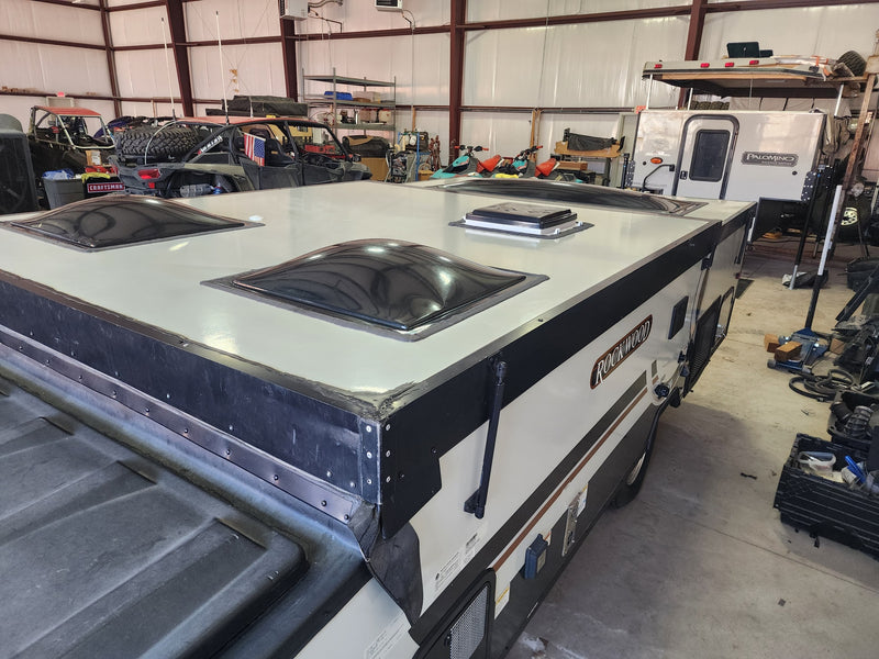 A Rockwood pop-up camper's roof with skylights, ideal for an RV rental. Workshop scene with UTVs, jet skis, & a Palomino camper. — photo 13