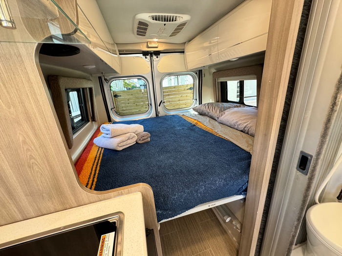  and overhead storage.|Cozy RV rental interior with a bed featuring a blue blanket