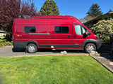 This bright red Winnebago Solis RV rental (camper van) is parked on a sunny driveway, ready for travel.