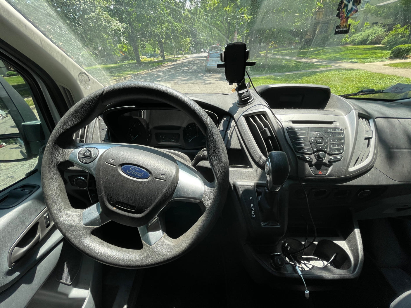 Interior view of a Ford Transit van, common for commercial or rv rental conversions. Driver's perspective of dashboard & street.