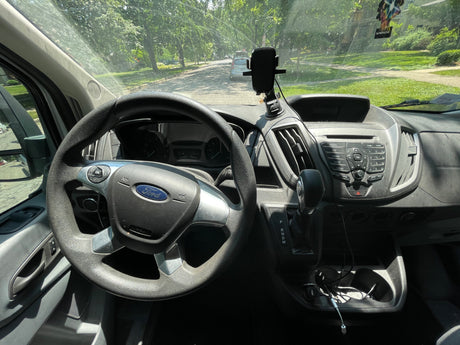 Interior view of a Ford Transit van, common for commercial or rv rental conversions. Driver's perspective of dashboard & street.