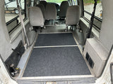 RV rental: View inside a modified van with multi-passenger seating and a wheelchair-accessible floor at the rear.