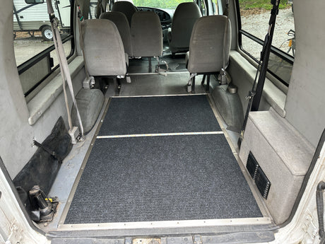 RV rental: View inside a modified van with multi-passenger seating and a wheelchair-accessible floor at the rear.