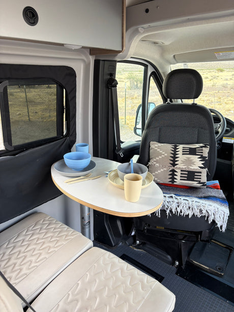 Cozy RV rental interior with a dining table set for two, perfect for a camper van adventure. Features seating and kitchenware.