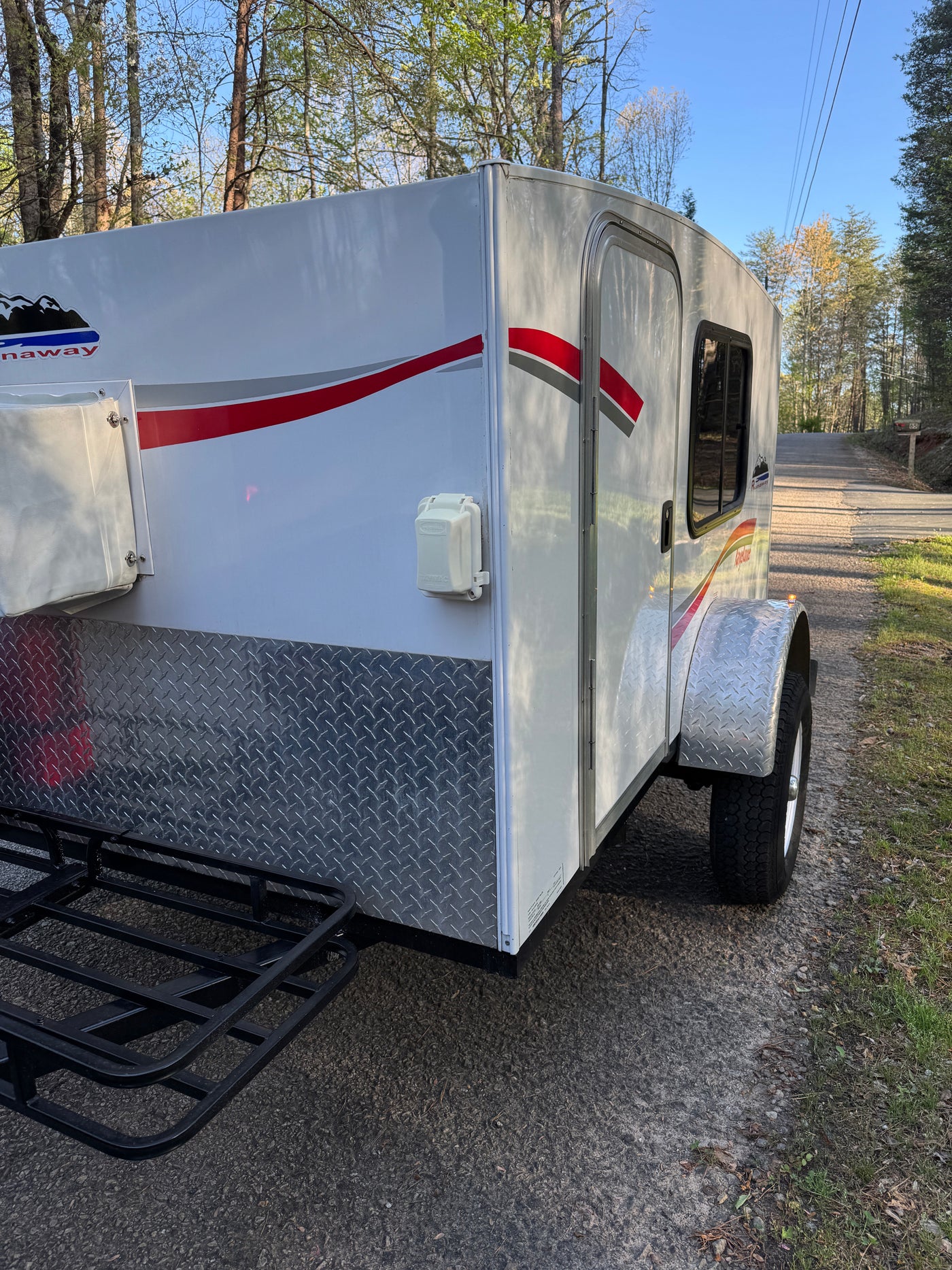 This white Runaway compact camper is ideal for your next rv rental. Shown with diamond plate trim, side door, and cargo rack. — photo 3