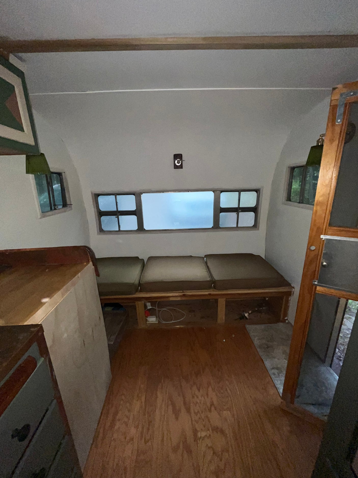 Cozy **rv rental** interior: light wood floor, bright windows, comfy bench seating. Ideal living space for travel.
