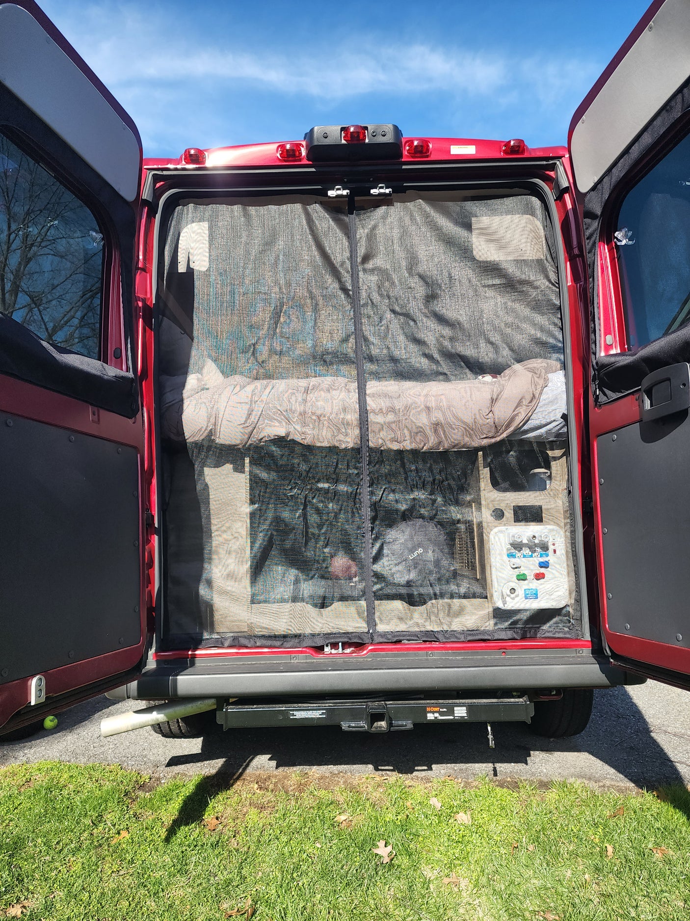 Inside an RV rental van: rear view showing mesh screen, sleeping area, and control panel.