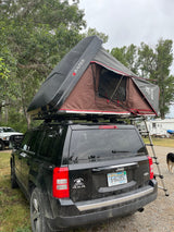  set up for camping. An exciting RV rental for outdoor adventures.|An RV rental SUV with a deployed rooftop tent. Inside
