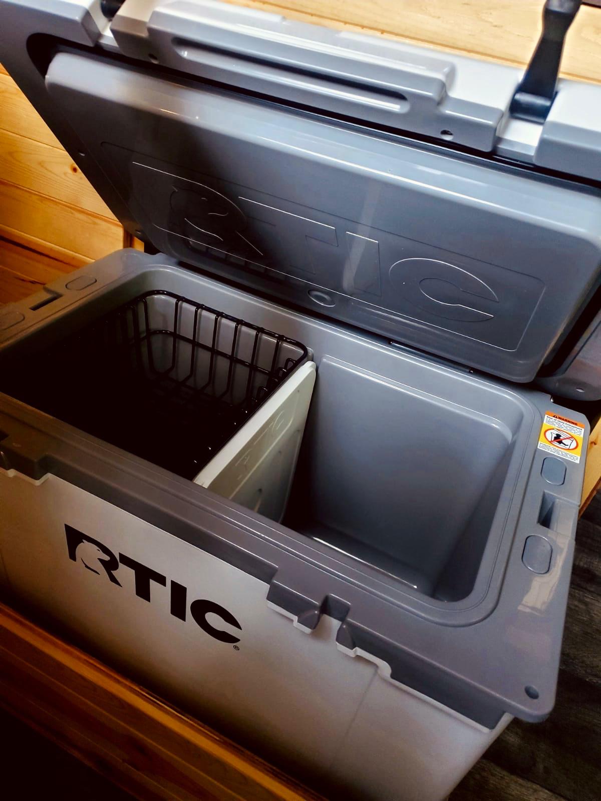 An open gray RTIC cooler with internal basket & divider for organized portable storage, ideal for your rv rental getaway.