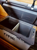 An open gray RTIC cooler with internal basket & divider for organized portable storage, ideal for your rv rental getaway.
