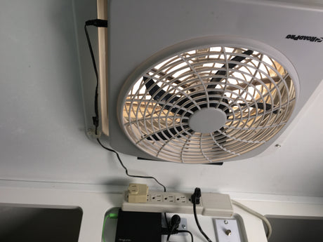 RV rental ceiling fan, power strip, and electronics are seen, providing comfort and connectivity in a compact space.