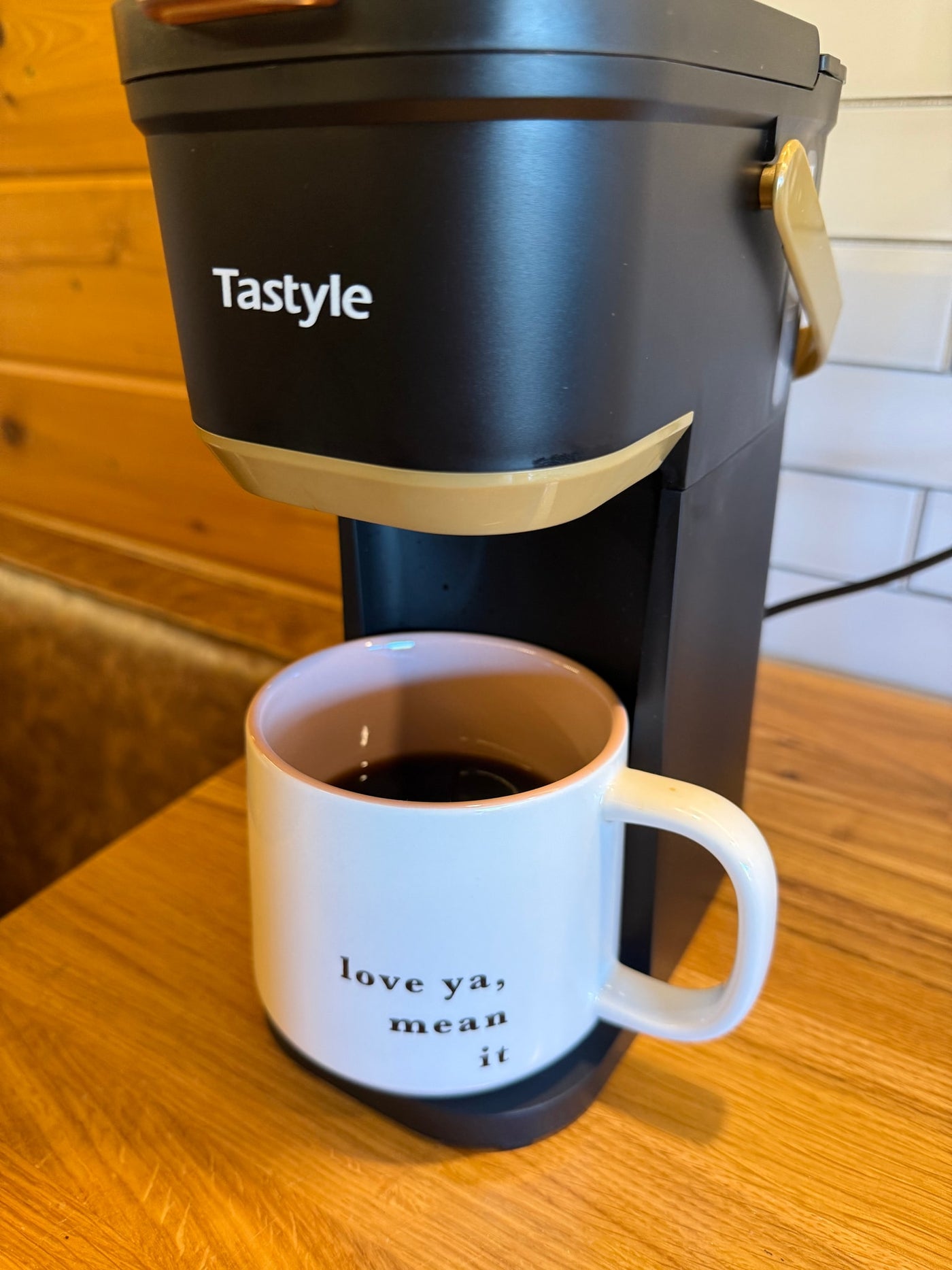 Cozy morning in an RV rental with a compact Tastyle coffee maker pouring into a white mug that reads "love ya, mean it." — photo 15