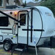White and grey compact GEO PRO travel trailer with awning extended and steps down, ready for an RV rental camping trip.