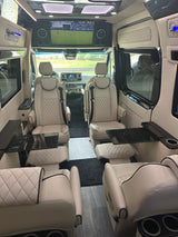 Step inside this luxury RV rental: comfortable, quilted captain's chairs, a large entertainment screen, and sleek tables for travel comfort.