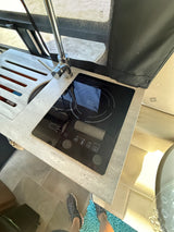 Compact RV rental kitchen features a modern induction cooktop, sink, and stylish countertop, ideal for travel.