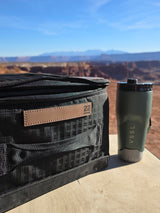 Road trip views! This RV rental stop features a black bag and VSSL thermos on a wooden surface, overlooking a stunning canyon.
