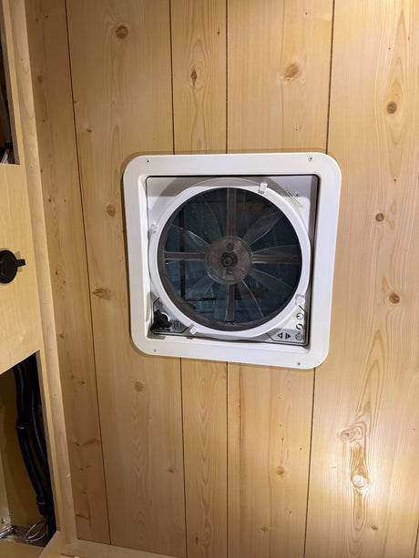 Inside an rv rental: a white Maxx Fan installed in knotty pine wood paneling, offering essential ventilation.