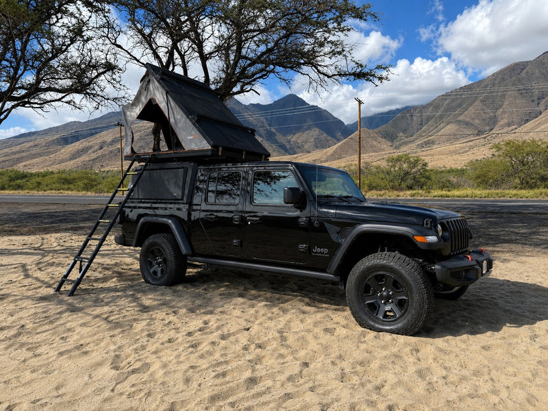 Black Jeep Gladiator with rooftop tent for your next RV rental adventure. Parked on sand, ready for camping in nature. — photo 1