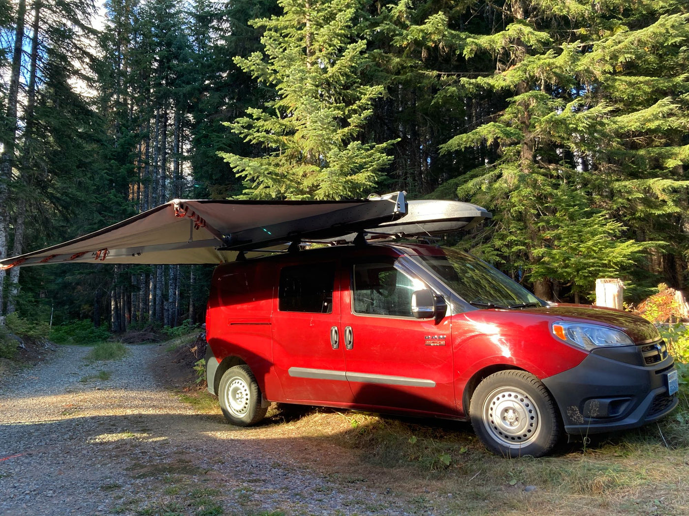 Red ProMaster City RV with extended awning, parked on a forest path. Ideal for rv rental camping adventures. — photo 2