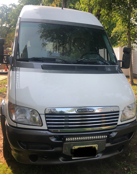 Front view of a white Freightliner Sprinter van, perfect for rv rental. This camper conversion is ready for adventure.
