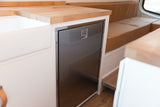 Functional RV rental kitchen: built-in stainless steel fridge, white sink, and butcher block countertop for compact living.