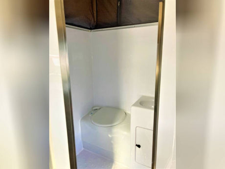 This RV rental features a compact, all-in-one bathroom with a toilet, sink, and shower enclosure for convenience.