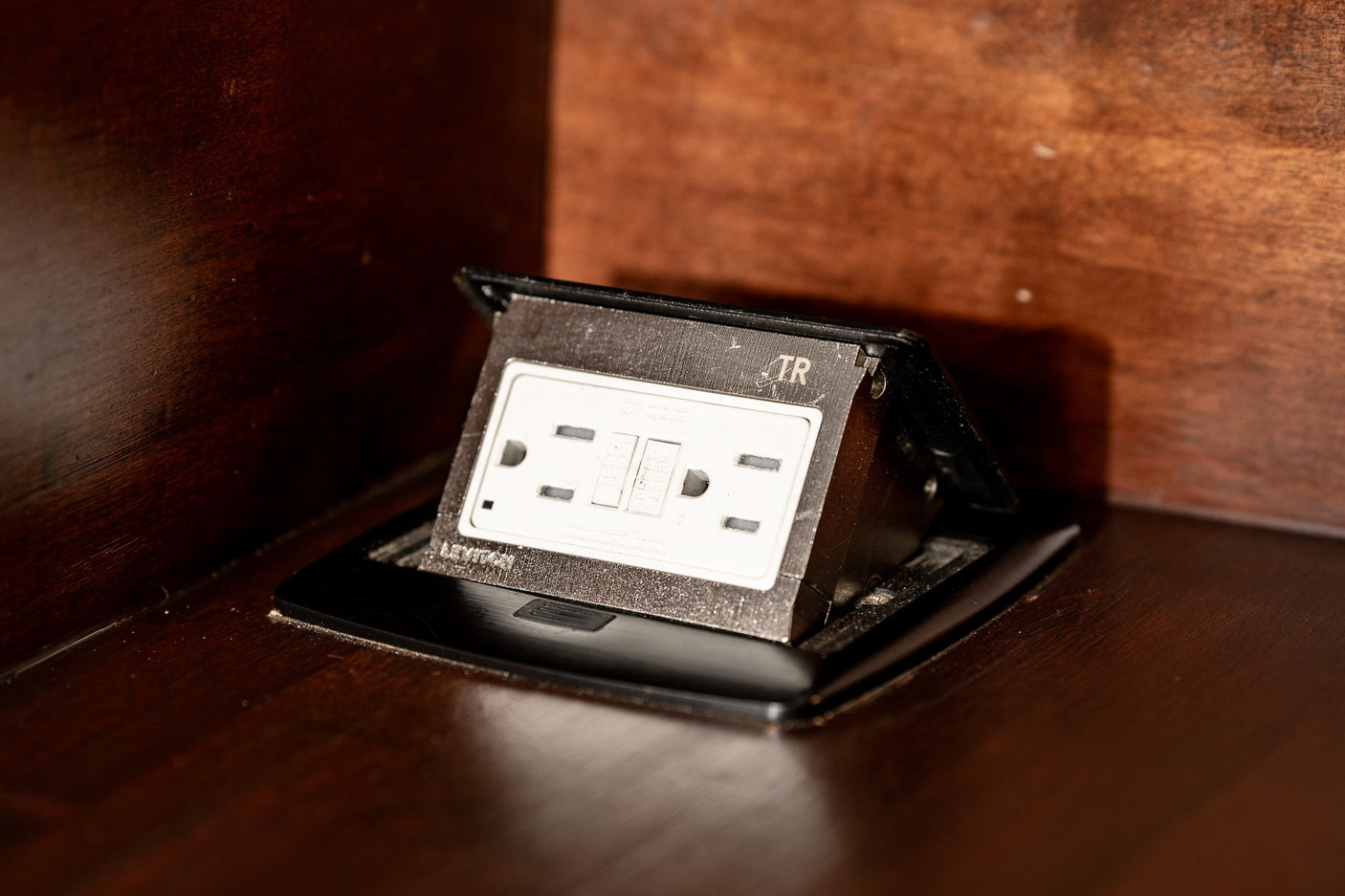 Dusty integrated GFCI outlet in dark wood furniture, providing convenient power for your RV rental.