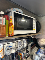 A compact RV kitchen featuring a microwave, spices, and clever storage solutions, ready for your next RV rental journey.