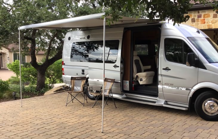  parked on a paver patio with chairs. Ideal for travel.|This silver Mercedes-Benz Sprinter RV — photo 2
