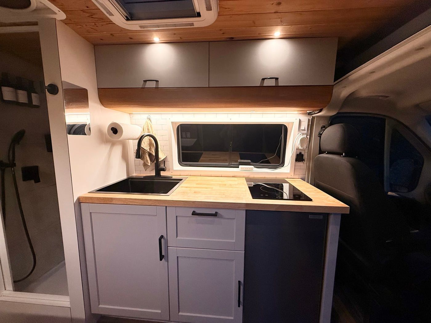  bathed in warm lighting.|Light green Ram ProMaster camper van (RV rental) parked on gravel — photo 4