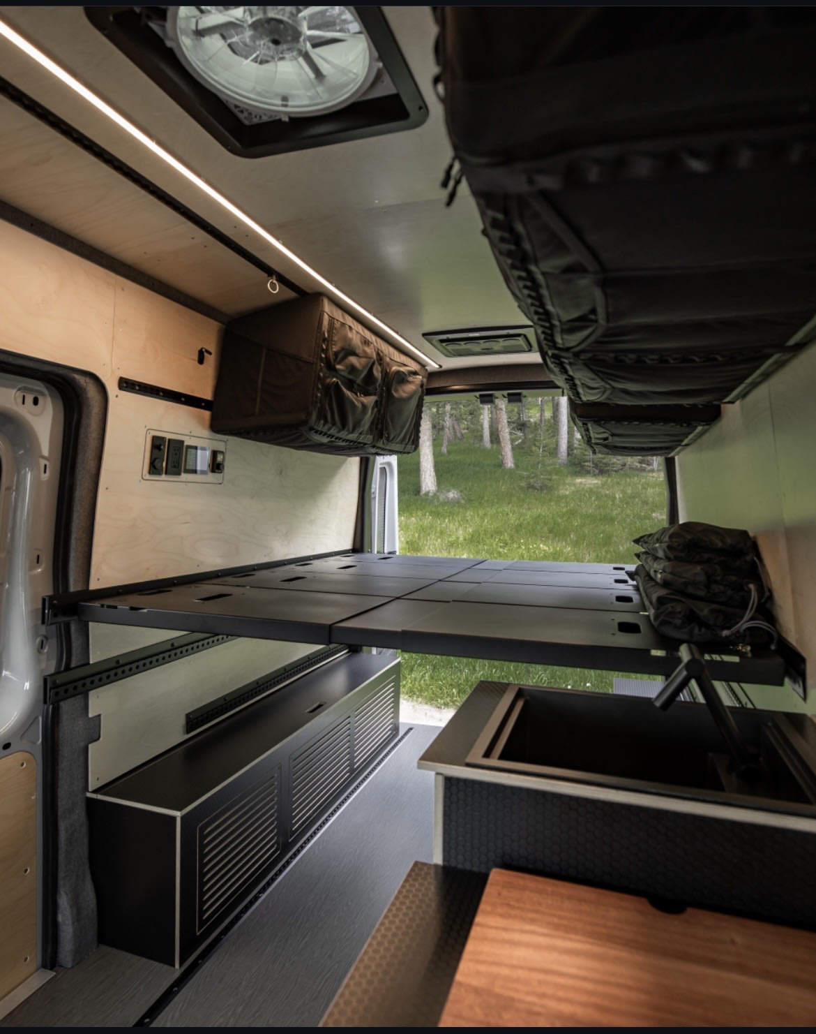 Spacious RV rental interior with a raised bed, modern kitchen sink, and ample storage for comfortable van life adventures.