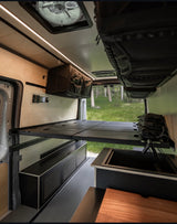 Spacious RV rental interior with a raised bed, modern kitchen sink, and ample storage for comfortable van life adventures.