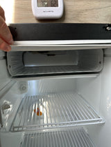 Inside a clean, empty compact refrigerator, typical for an RV rental. Features include a top freezer compartment and wire shelves.