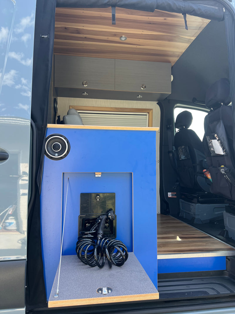 This rv rental's interior features a blue cabinet with a pull-out outdoor shower, overhead storage, and a warm wooden ceiling. — photo 9