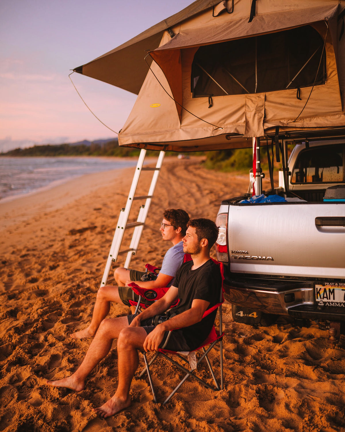 Two men enjoy beach sunset from a rooftop tent on a truck. An ideal outdoor adventure, perfect for an rv rental! — photo 7